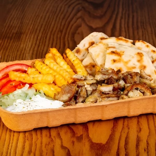 Shawarma Zone platter with chicken shawarma, fries, pita bread, tomatoes, onions, and sauce.